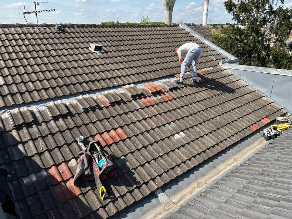 Couvreur posant des tuiles sur une toiture dans le Loiret
