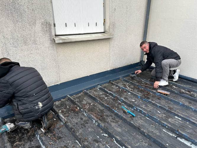 Couvreur en train de démousser une toiture